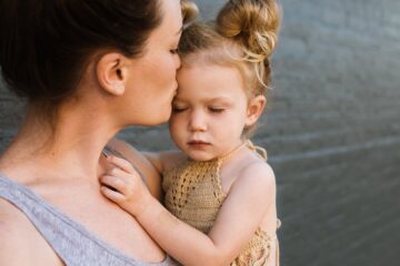 A mother holds and kisses her child. Image: Pixabay.