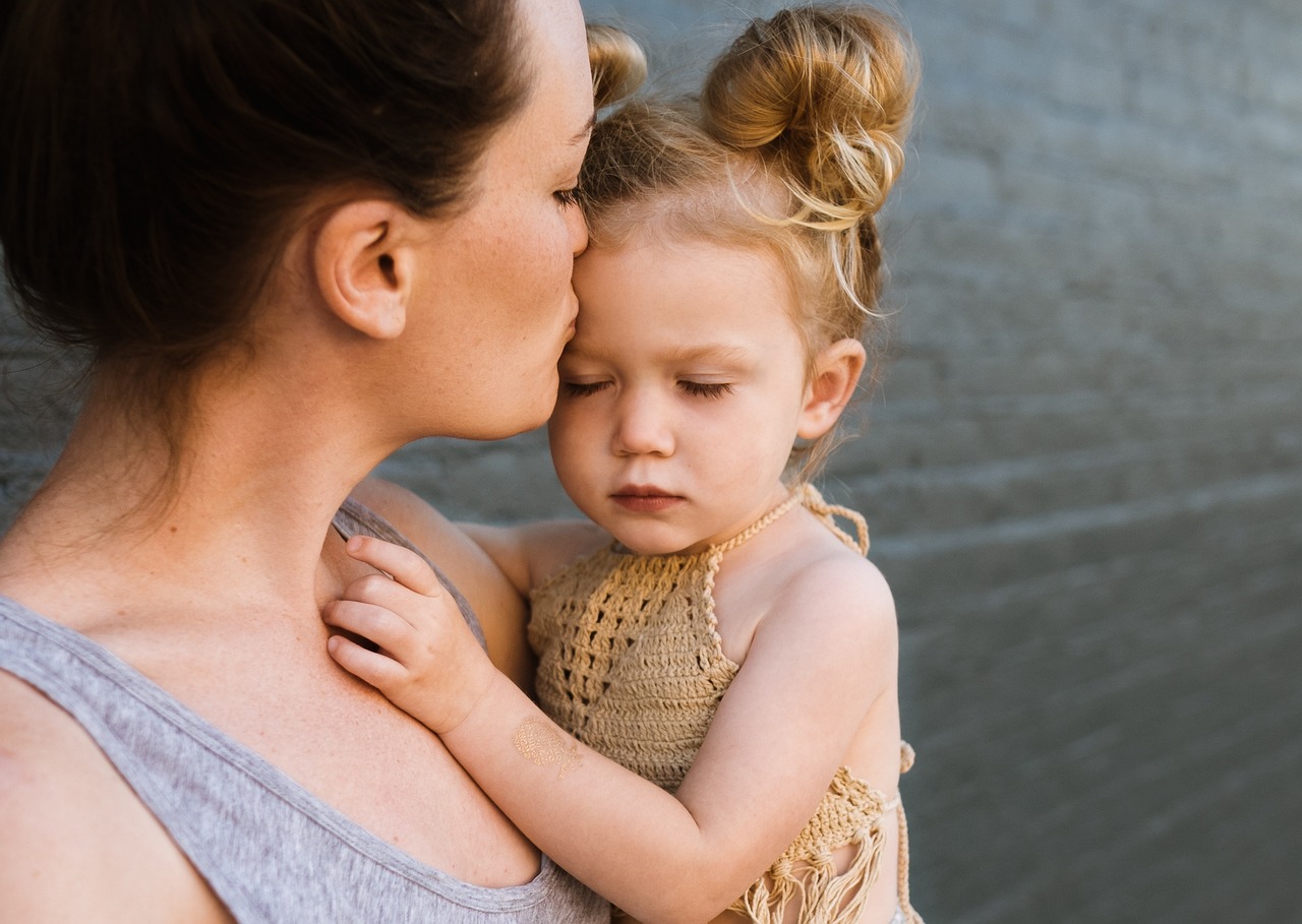 A mother holds and kisses her child. Image: Pixabay.