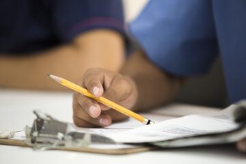 Hand holding pencil and paper.